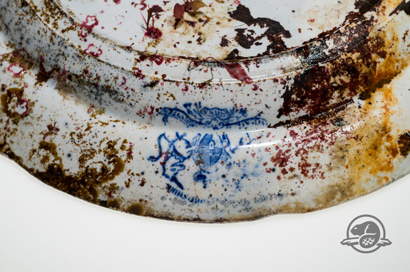 O imagine detaliată a unei plăci ceramice găsite la bordul HMS Erebus. Această placă a fost decorată cu modelul comun de salcie albastră și este marcată „Royal Patent Staffordshire China.”